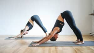 Two women doing a yoga pose in a workout studio on yoga mats