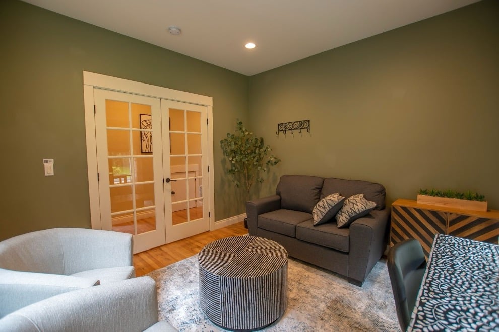 Mission Connection comfortable therapy room with sage green walls, gray and cream furniture