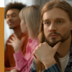 man looking into the distance pensively while others talk behind him, wondering if he should seek social anxiety treatment for his social phobia