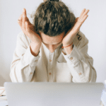 Man with head in hands after a long workday, showing workplace anger
