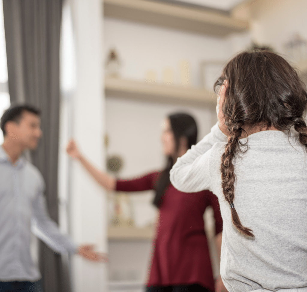 Parents yelling at each other while child puts hands over ears