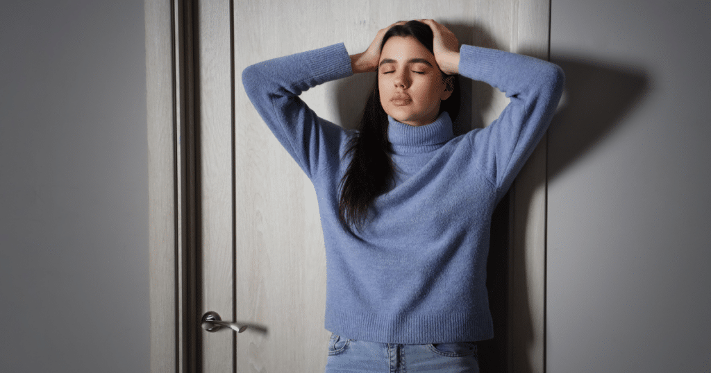 Woman leaning against the door managing anxiety attack