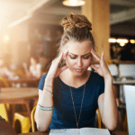 woman looking at book with fingers pressing on the sides of her head, wondering, "What is Klonopin?"