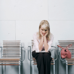 woman with head in hands, sitting and waiting, wondering, "What is Xanax and how can it help my anxiety?"