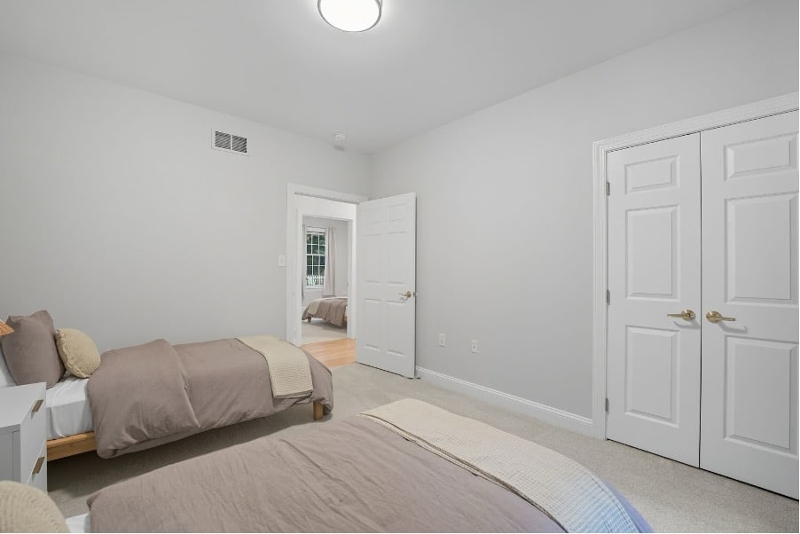 Clean minimalist Mission Connection facility bedroom with twin beds, neutral gray and white decor.