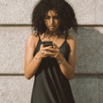 woman looking at phone to rely on partner validation and contact, experiencing codependency