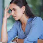 woman looking at workplace computer with graphs on a sheet in front of her, feeling frustration due to her attachment styles at work