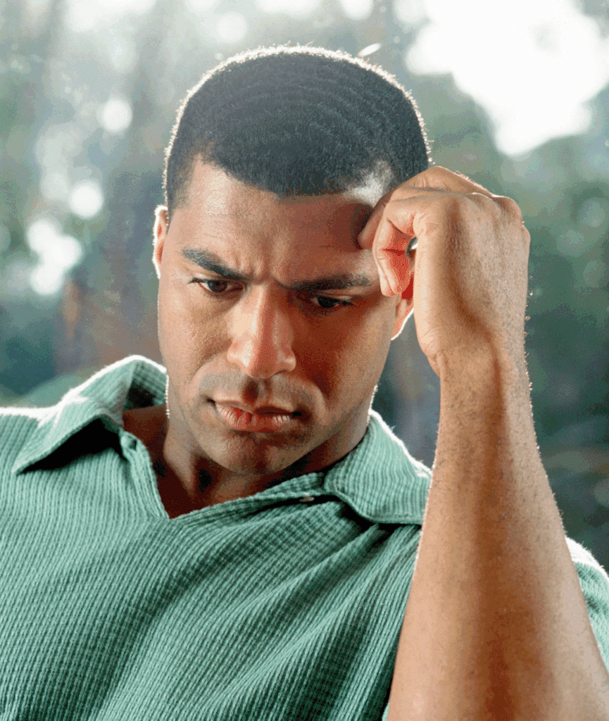 man looking down with hand on head considering the treatment approaches for dissociative identity disorder