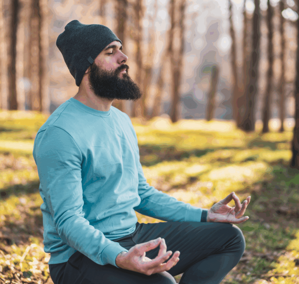 Man sitting in the forest with his legs crossed, meditating as a coping strategy for adjustment disorder