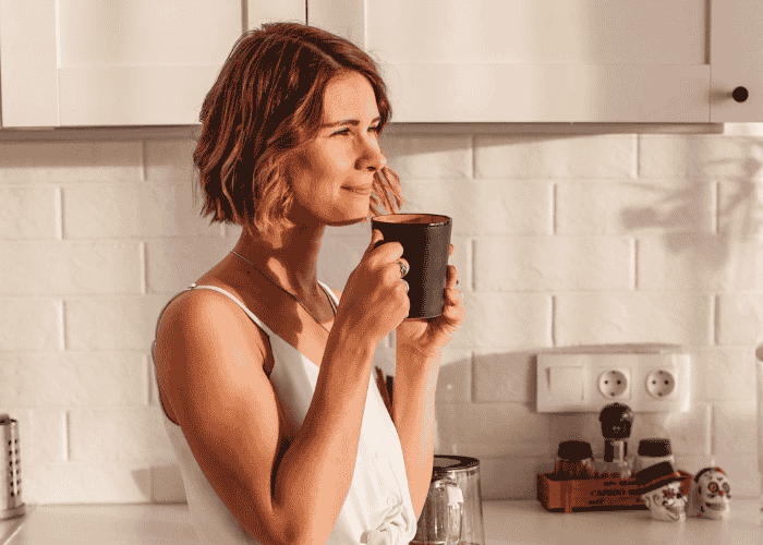 woman drinking coffee and smiling after getting treatment for types of adjustment disorders