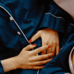 Woman in pyjamas clutching her stomach because of nausea from stress or anxiety