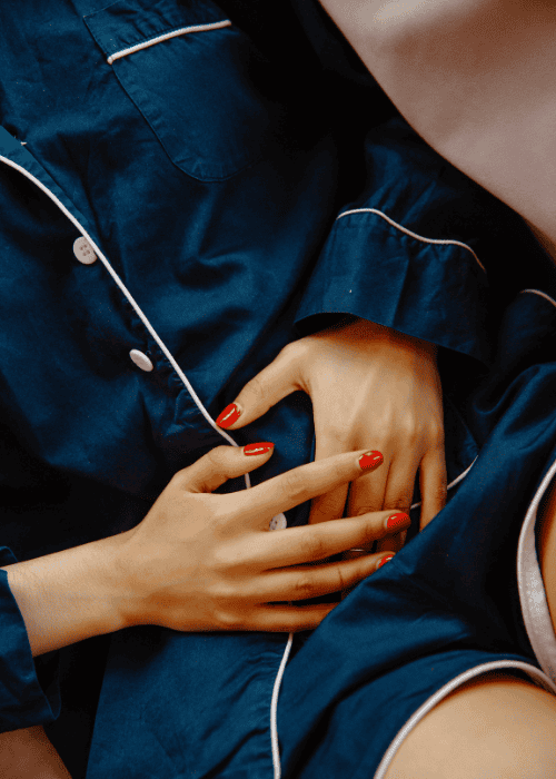 Woman in pyjamas clutching her stomach because of nausea from stress or anxiety