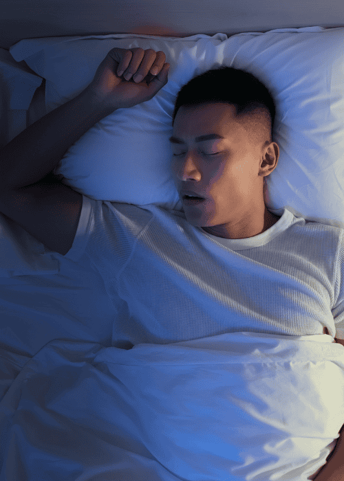 man in bed sleeping deeply, experiencing oversleeping & hypersomnia in adults