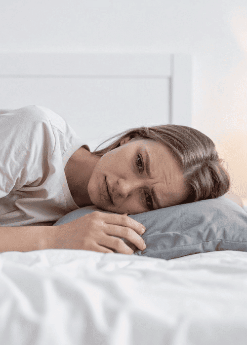 woman laying in bed frowning after experiencing sleep paralysis in adults