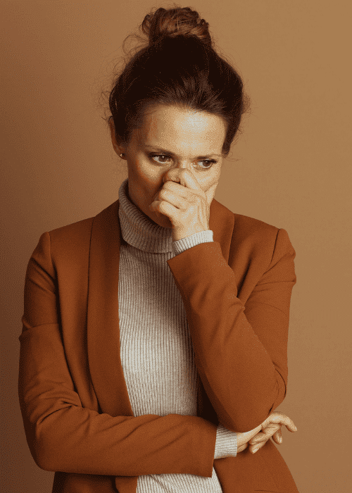 Woman covering mouth with hand nervously because of experiencing conflict avoidance in adults.