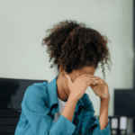 woman at work sitting at desk with head in hands due to overthinking & rumination in adults
