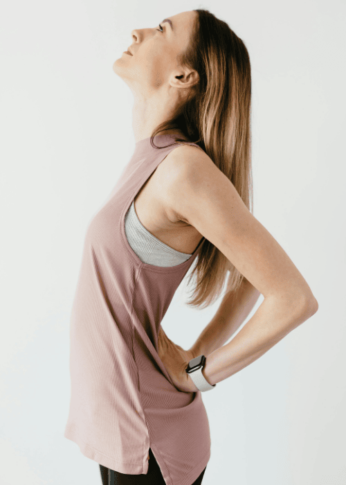 woman with hands on hips arching back due to muscle tension & trembling in adults