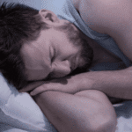 man asleep in bed experiencing nightmares in adults