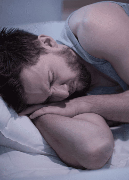 man asleep in bed experiencing nightmares in adults