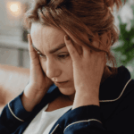 woman sitting in lounge with hands on head looking confused due to disorientation & confused thinking in adults