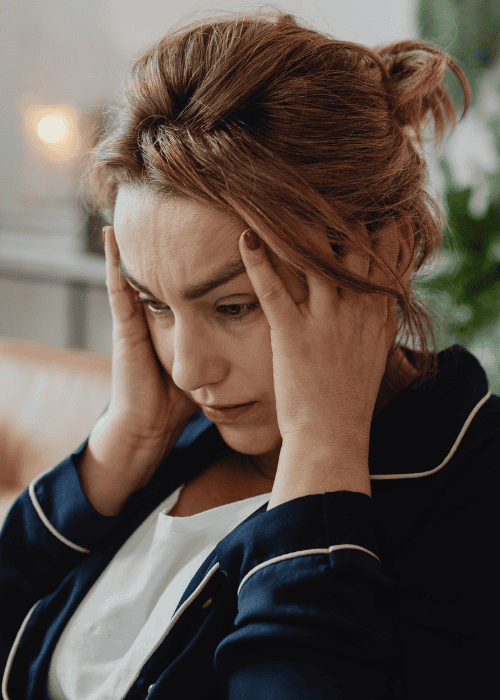 woman sitting in lounge with hands on head looking confused due to disorientation & confused thinking in adults