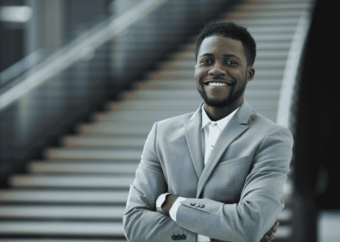 man outside with steps behind him smiling with arms crossed after treatment for muscle tension and trembling in adults