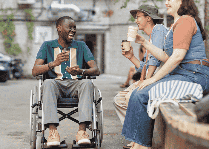 man outside smiling drinking coffee with friends after receiving support for approval-seeking behavior in adults