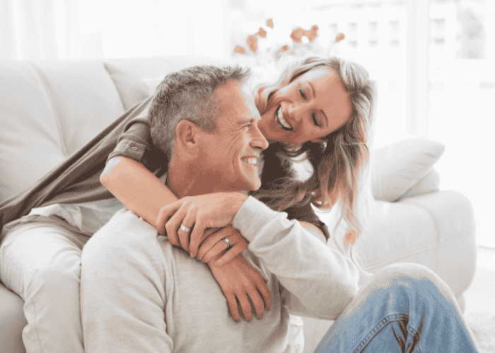 Couple sitting on sofa cuddling after treatment for trouble trusting others in adults.