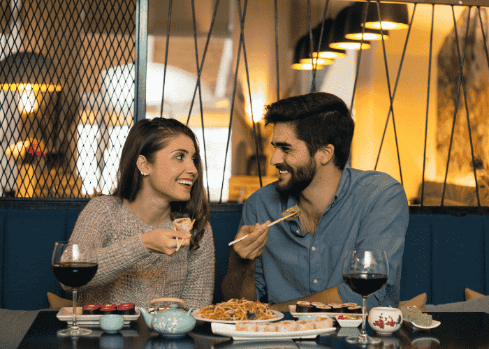 A couple eating dinner in a restaurant smiling at each other after receiving support for loss of appetite in adults.