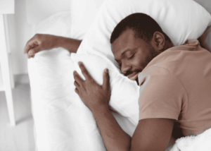 Man sleeping deeply on pillow in bed with tan shirt on