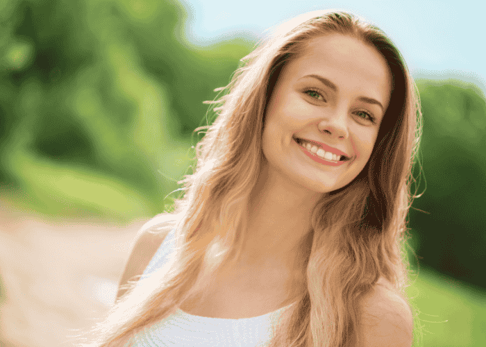 blonde, long-haired woman smiling at the camera after receiving treatment for emotional numbness in adults
