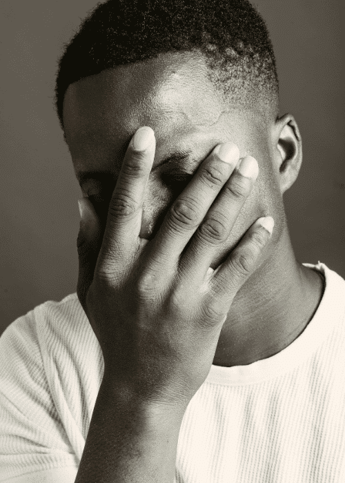 Man with his head in his hand struggling with excessive guilt & shame in adults