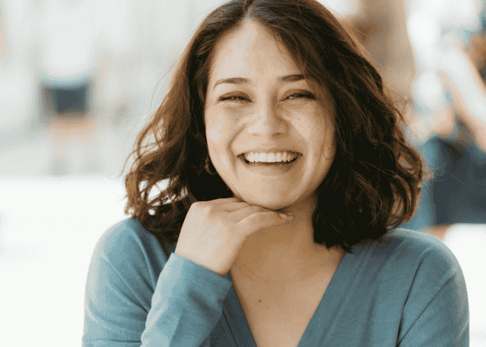 woman smiling at the camera with her hand under her chin after overcoming excessive guilt & shame in adults