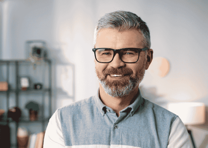 Middle-aged man with glasses smiling at the camera after treatment for overreactions in adults