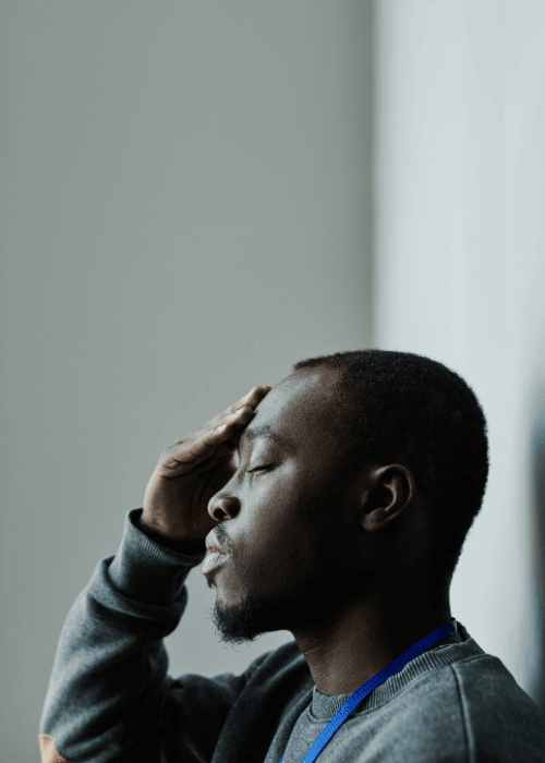 Man with his eyes closed touching his head because he struggles with headaches related to stress & anxiety in adults
