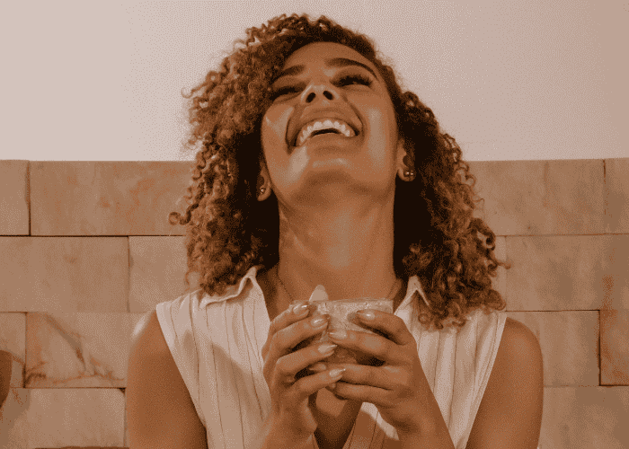 Woman holding a coffee cup looking up with a look of relief after treatment for headaches related to stress & anxiety in adults