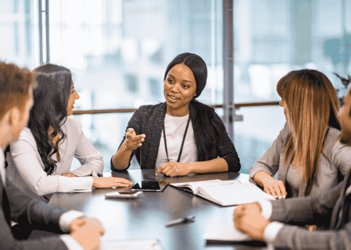 Woman in a meeting smiling and giving directions as she's received treatment for indecisiveness in adults