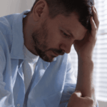 Man sitting with head in hand, experiencing emotional and behavioral signs