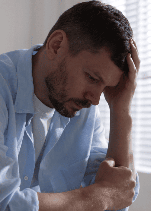 Man sitting with head in hand, experiencing emotional & behavioral symptoms in adults