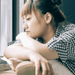woman experiencing social & interpersonal difficulties in adults sitting alone by a window