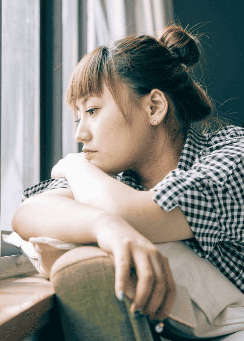 woman experiencing social & interpersonal difficulties in adults sitting alone by a window