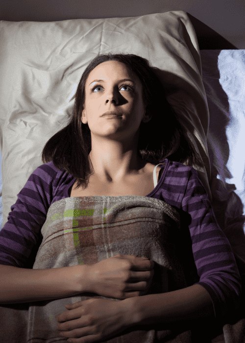 Woman in bed awake staring at ceiling experiencing problems sleeping in adults