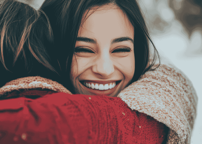 Woman smiling as she hugs a friend after treatment for emotional and behavioral symptoms.