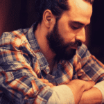 Man sitting in bar with arms crossed looking sad due to experiencing Anhedonia in adults