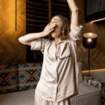 tired woman in bedroom in pyjamas yawning and stretching after experiencing parasomnias in adults
