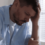 man leaning on desk with head in hand due to experiencing hopelessness in adults