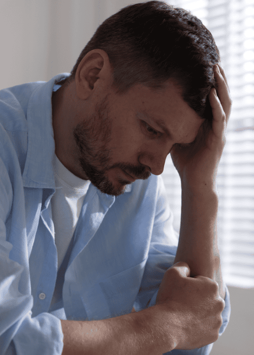man leaning on desk with head in hand due to experiencing hopelessness in adults