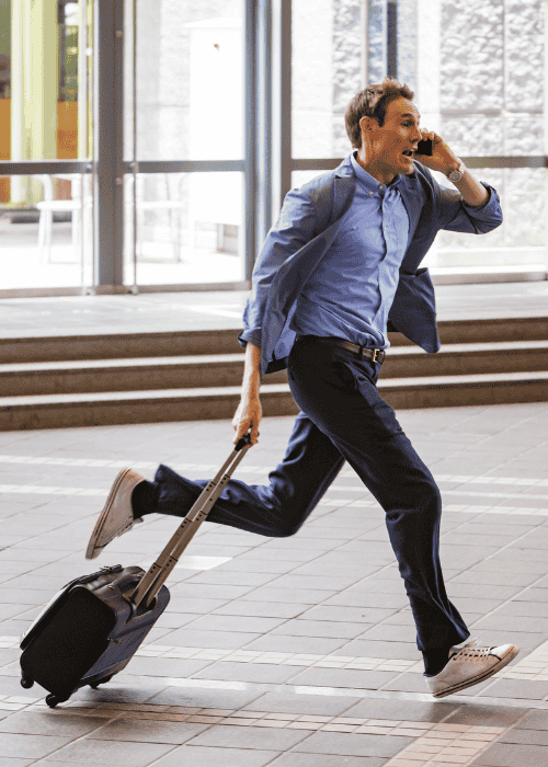 man dressed for work running pulling suitcase behind him on phone because he is late after experiencing a distorted sense of time in adults