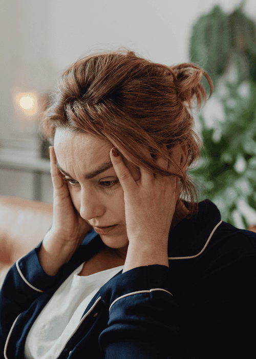 woman sitting in living room with head in hands due to experiencing processing difficulties