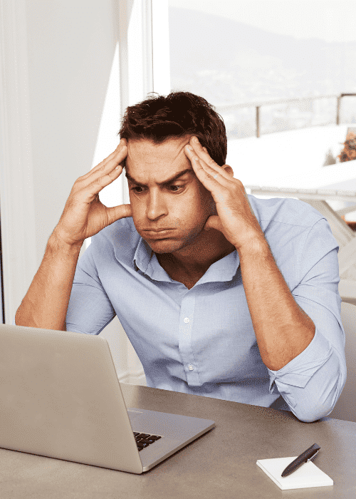 man sitting at desk with laptop with head in hands and exhaling with frustration due to loss of objectivity